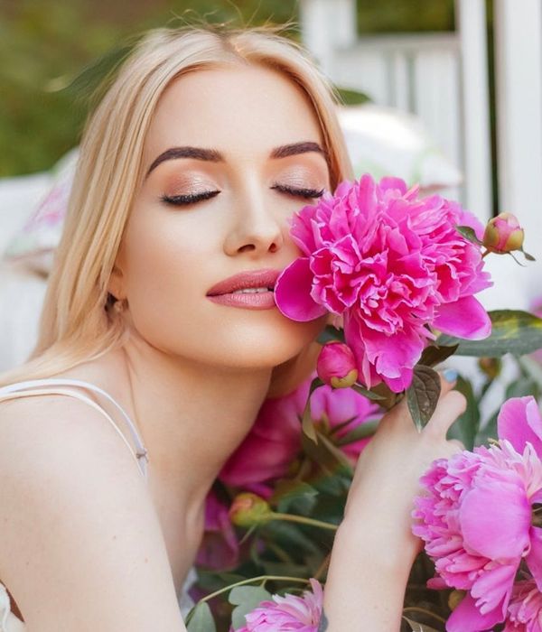 Woman in a serene yoga pose, bathed in soft pink light, embodying tranquility.